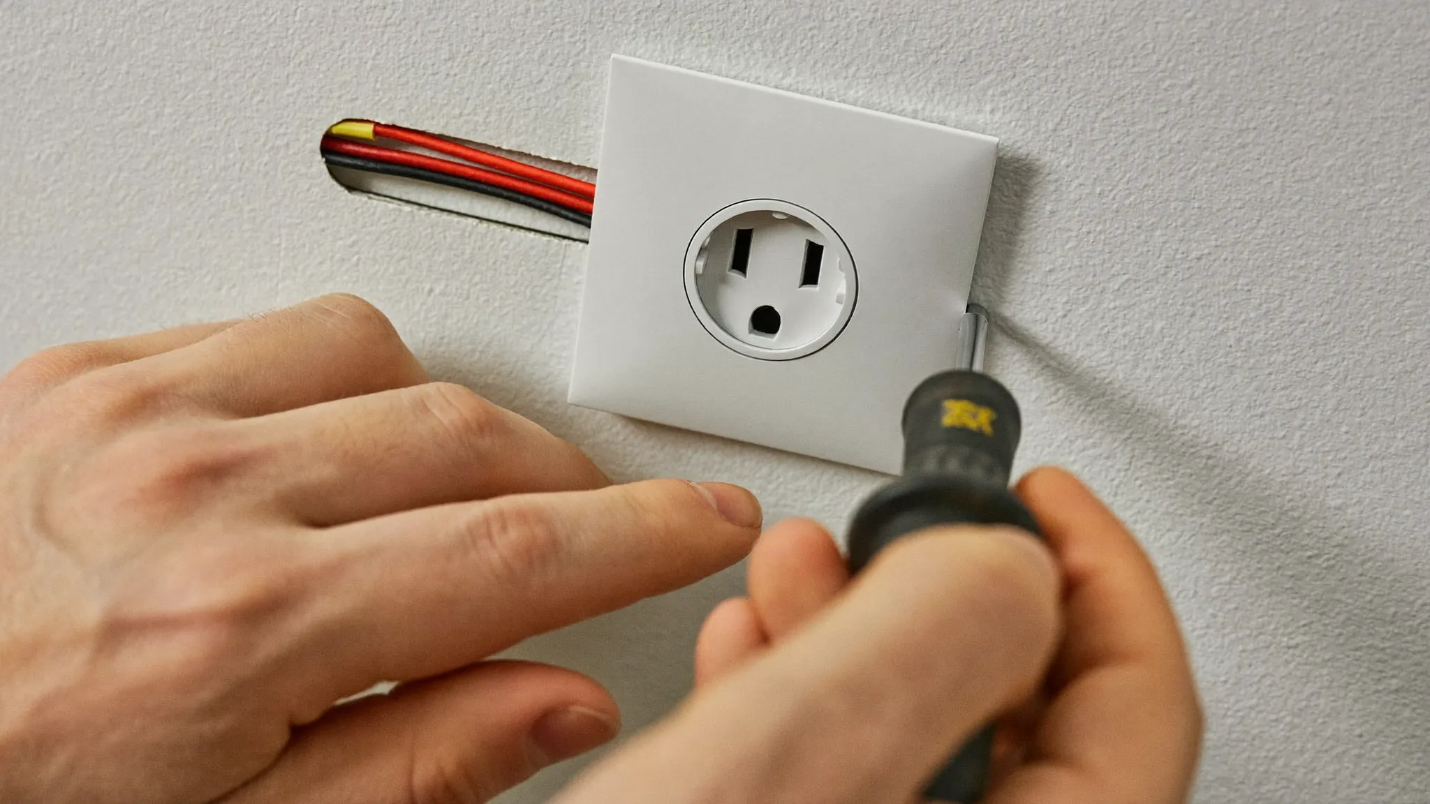 Manos de electricista instalando un enchufe de pared nuevo en una vivienda de Sant Cugat del Vallès